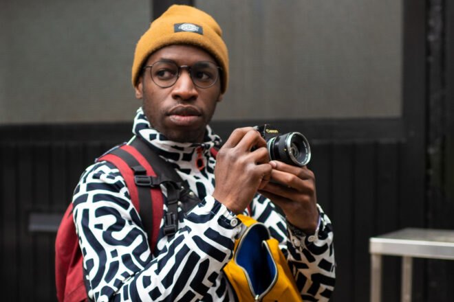 person in black and white patterned jacket and taking photos