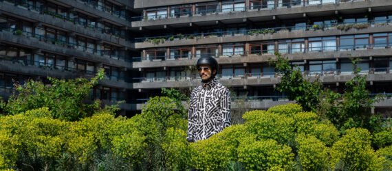 person wearing black and white patterned jacket surrounded by plants