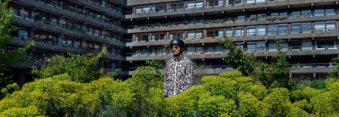 person wearing black and white patterned jacket surrounded by plants