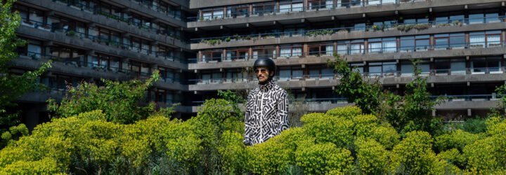 person wearing black and white patterned jacket surrounded by plants