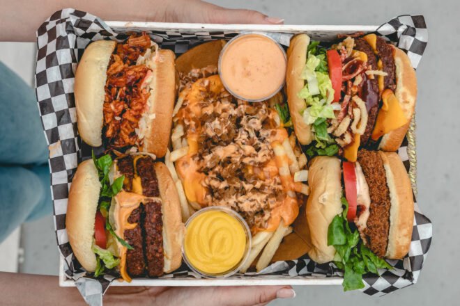vegan burgers, pulled pork sandwiches and chicken sandwiches on a metal restaurant tray