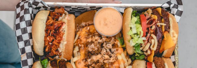 vegan burgers, pulled pork sandwiches and chicken sandwiches on a metal restaurant tray