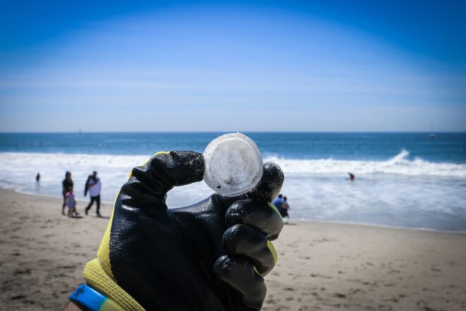 gloved hand holding trash on a beach