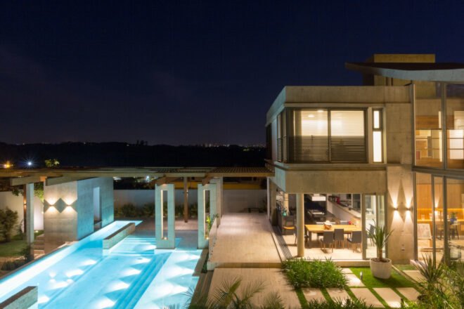 evening view of illuminated home with swimming pool