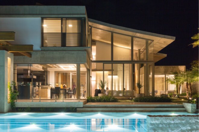 evening view of illuminated home with swimming pool
