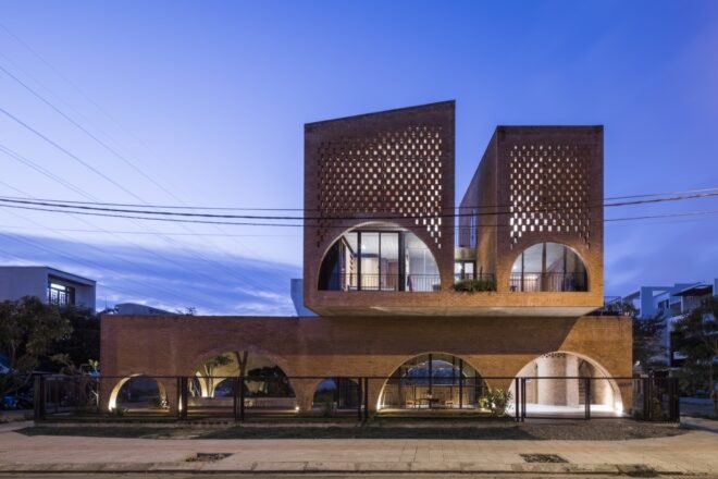 linear brick home with two additional brick volumes on second story at night