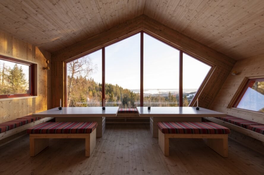 dining area with red benches and large tables next to massive geometric window