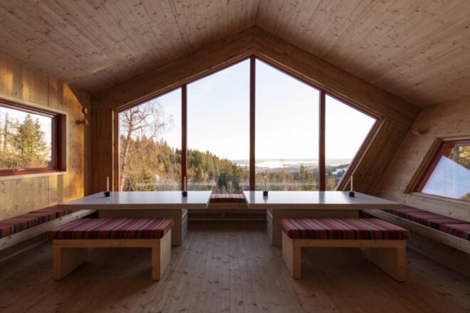 dining area with red benches and large tables next to massive geometric window