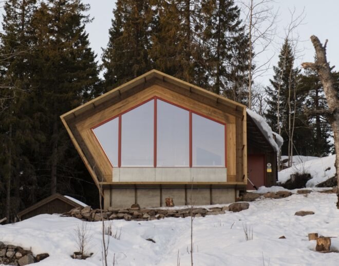 geometric wood cabin at top of snow-covered hillside