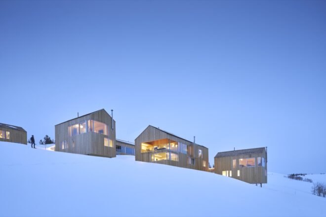 timber ski cabins surrounded by snow on a hill