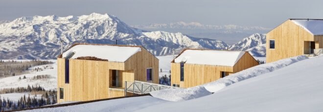 timber ski cabins surrounded by snow on a hill