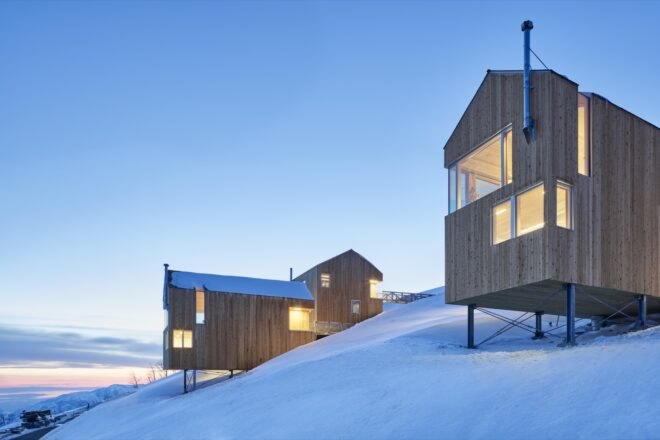 timber ski cabins surrounded by snow on a hill
