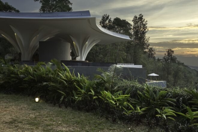white building with curvy roof overlooking hills