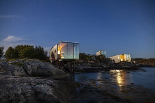 glass and aluminum cabin lit from within at night
