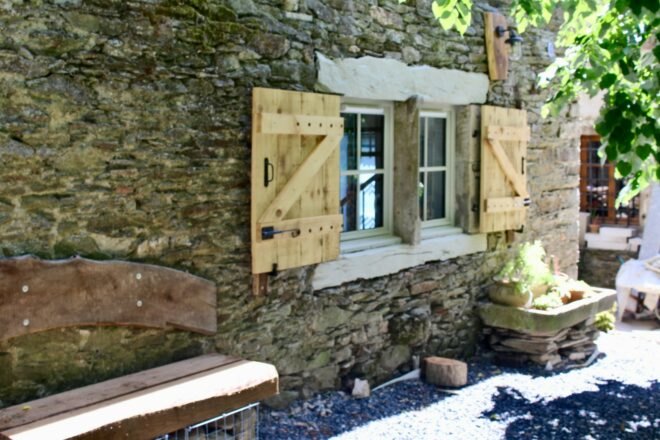 stone home with wooden shutters