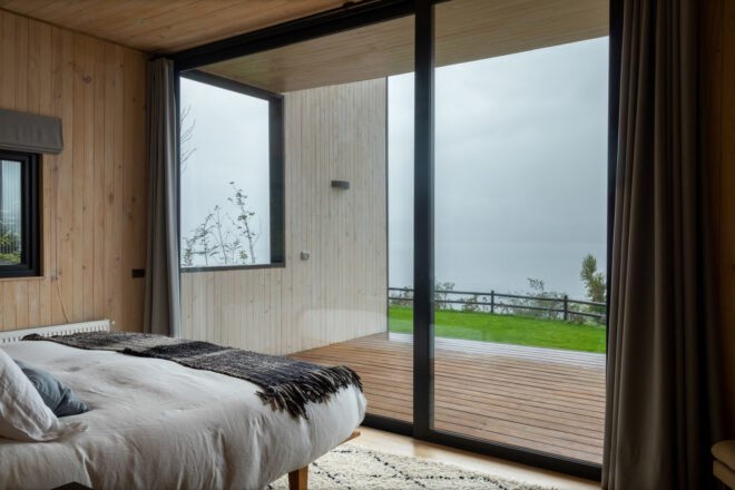 bed facing glass wall and wood deck