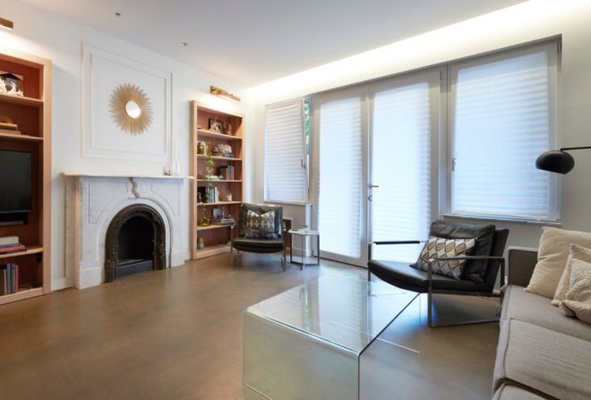 white living room with wood bookshelves and old white fireplace