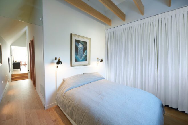 white guest bedroom with light wood ceiling beams