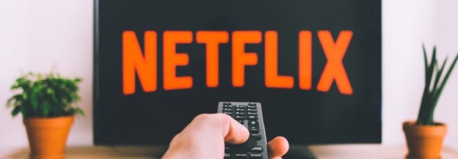 Person using remote to turn on Netflix on TV