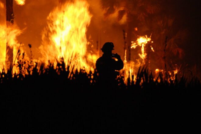 wildfire with firefighter in background