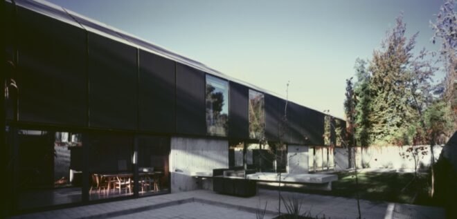 outdoor patio outside elongated black home with gabled roof