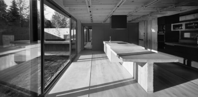 black and white image of concrete kitchen island next to sliding glass doors