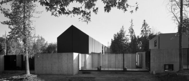 black and white photo of elongated black home with gabled roof