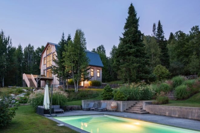 large barn home on green hill with swimming pool