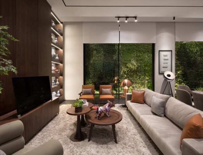 gray sofa facing dark wood wall with TV and bookcase with windows revealing a green wall