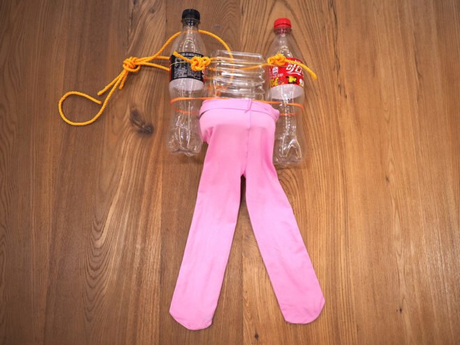 pink baby leggings attached to two plastic soda bottles