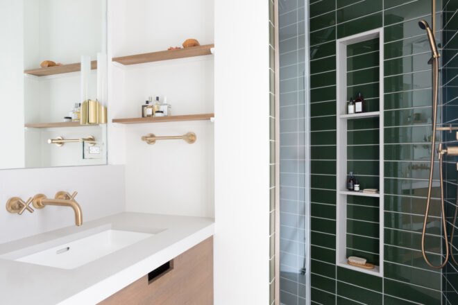 white and wood sink beside green-tiled shower