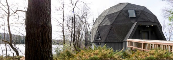 dark gray geodesic home by a lake
