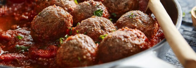 Beyond Meat plant-based meatballs simmering in a pan of marinara sauce