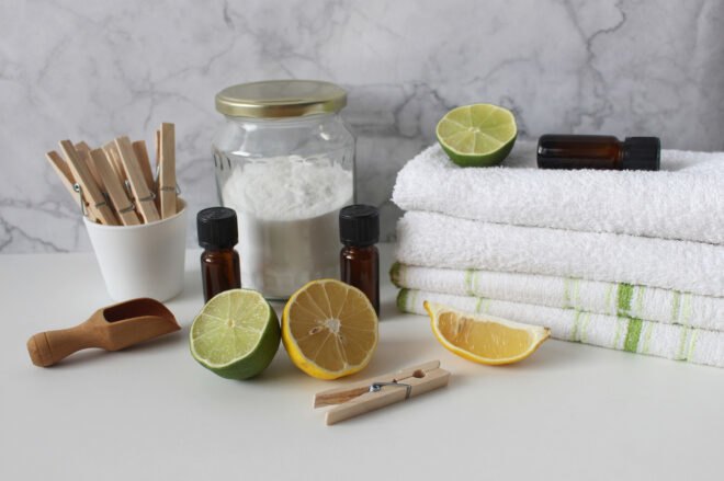 towels, homemade detergent and lemon and lime wedges on white table