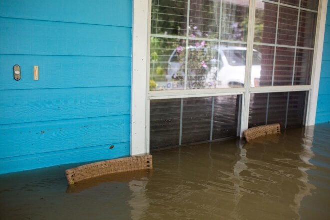 front porch of blue home flooded with stormwater