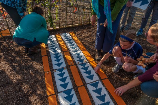 people laying paper embedded with seeds in a garden