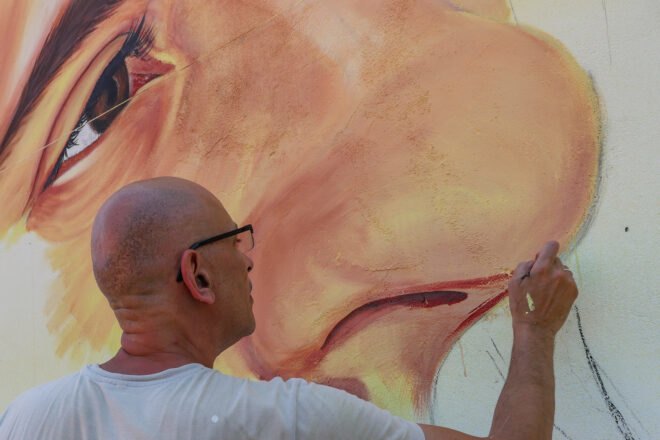 person painting a nose on a wall