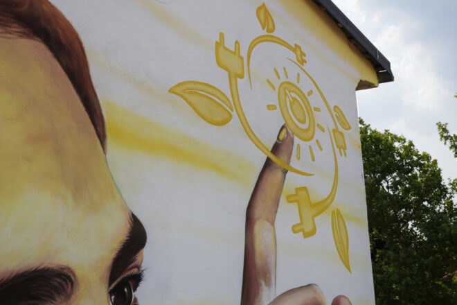 painting of hand touching symbols like a sun and a leaf on a wall