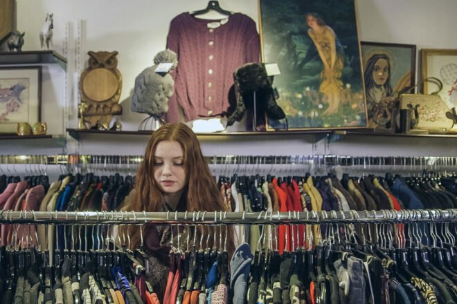 person looking through clothing racks in a thrift shop