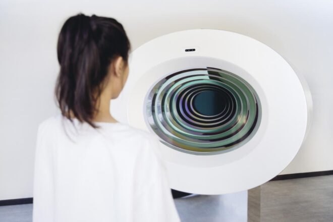woman looks at white circular device