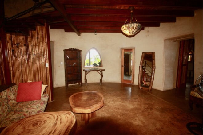 rammed-earth interior with tree trunk tables and wood-framed mirrors