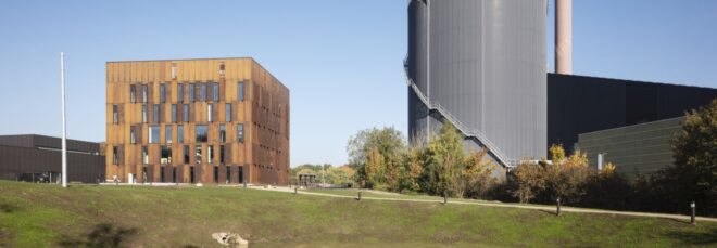 steel building surrounded by grass near a power plant