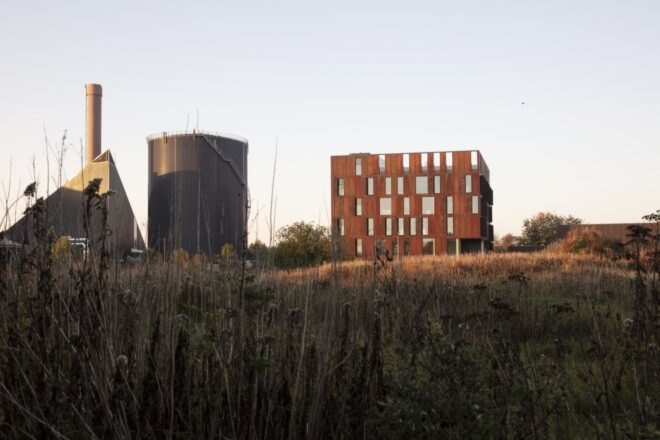 steel building surrounded by grass near a power plant