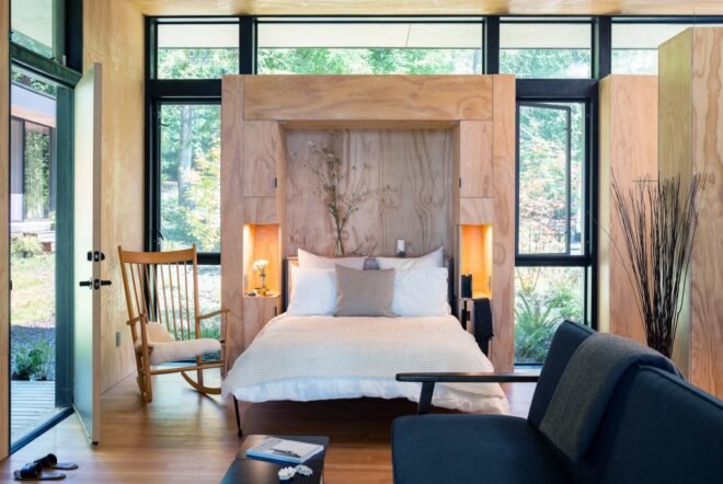 bedroom with large windows and wooden headboard with white bedding