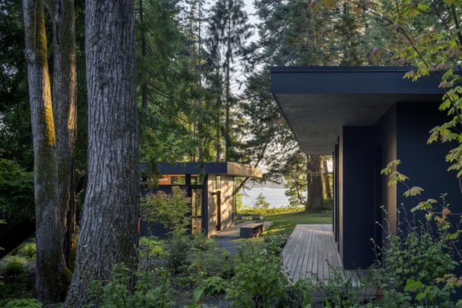 black modern cabin in forest with outdoor deck