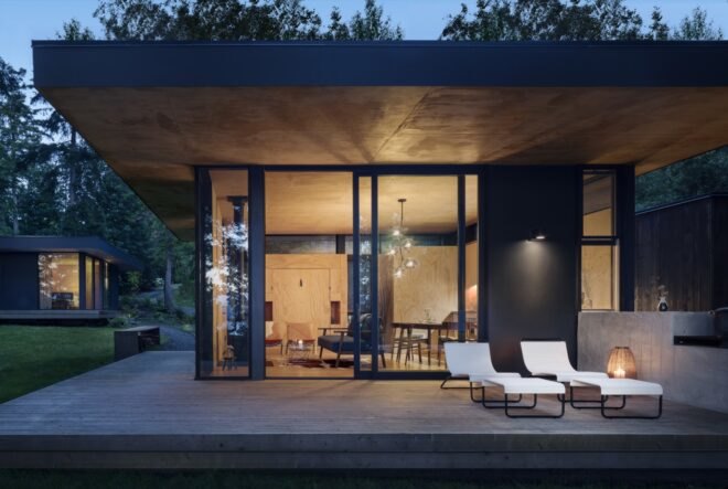 black modern cabin in forest with outdoor deck