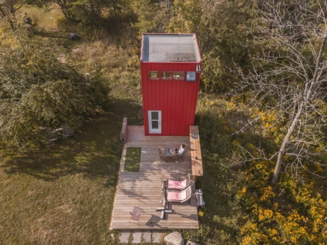 red metal tower with wooden deck in green field