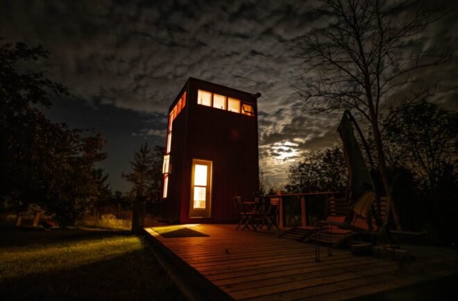 red tower with wooden deck in green field at night