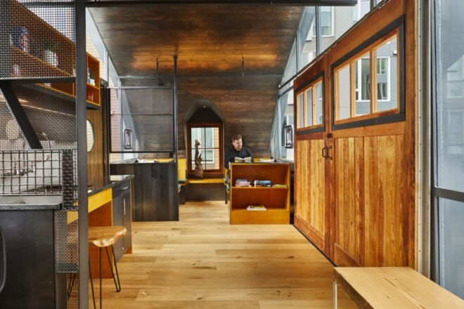 apartment with wood barn-style doors, a metal and wood kitchen and booths for dining