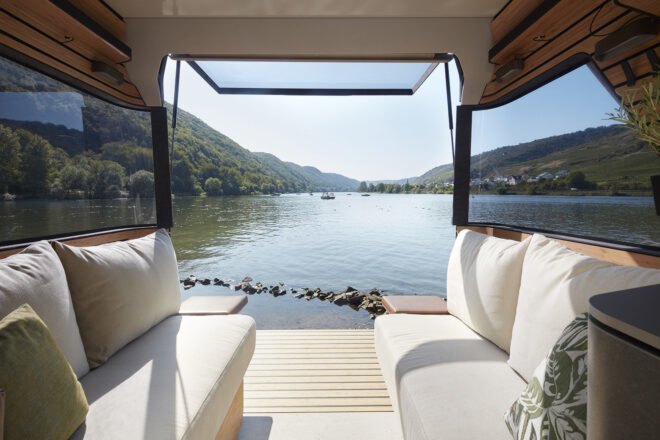 rendering of white couches in back of camper van with back door open to lake views